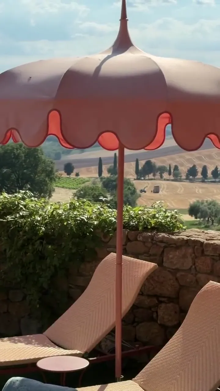 A pink scalloped parasol over the hills of Tuscany at Casa Newton