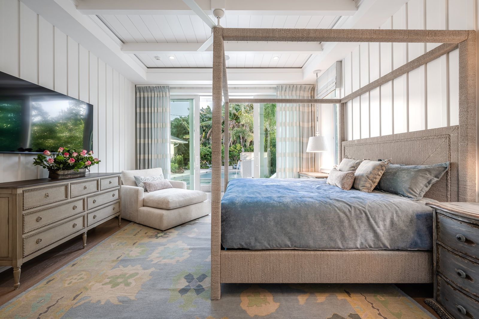Primary bedroom with four poster bed and paneled walls
