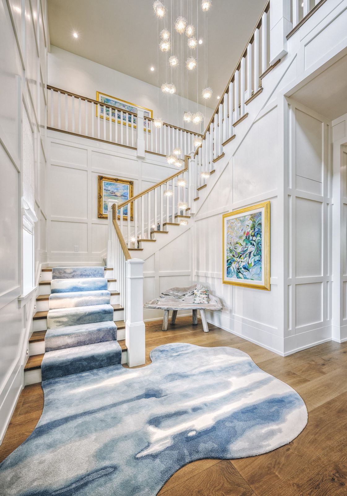 Two storey paneled stair hall with glass pendants